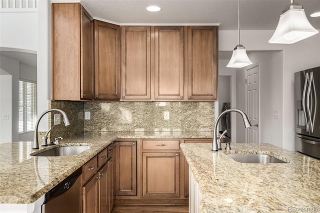 kitchen featuring stainless steel appliances, hanging light fixtures, sink, and light stone counters