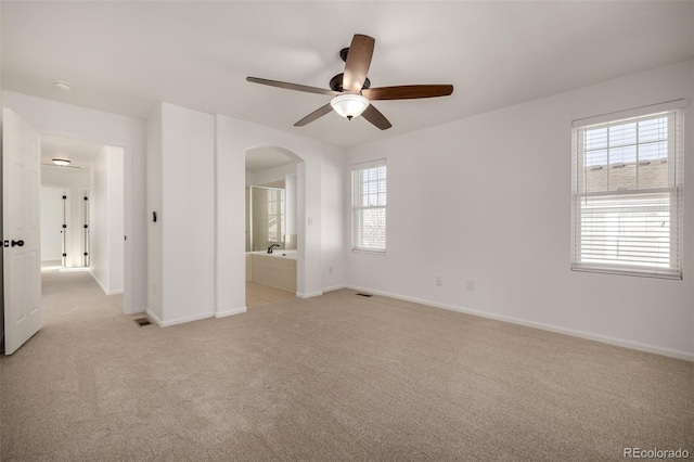 empty room featuring a healthy amount of sunlight, light carpet, and ceiling fan