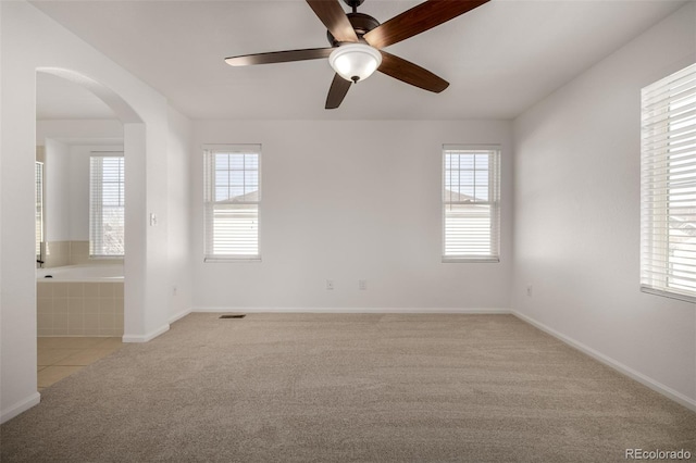 unfurnished room with light carpet, a wealth of natural light, and ceiling fan