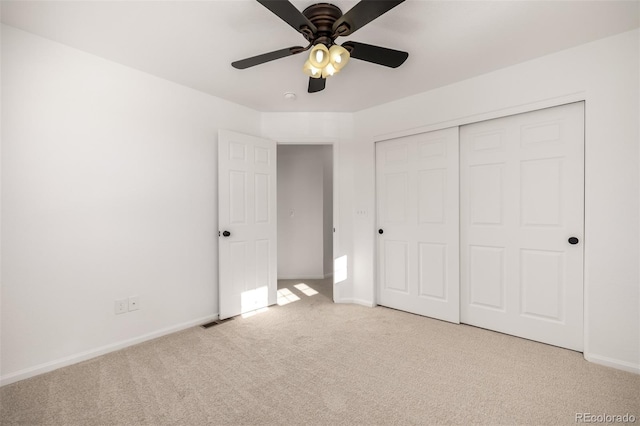 unfurnished bedroom with light carpet, ceiling fan, and a closet