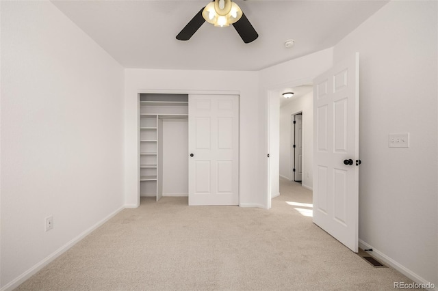 unfurnished bedroom with light colored carpet, a closet, and ceiling fan