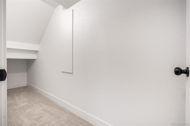 spacious closet featuring vaulted ceiling and light colored carpet