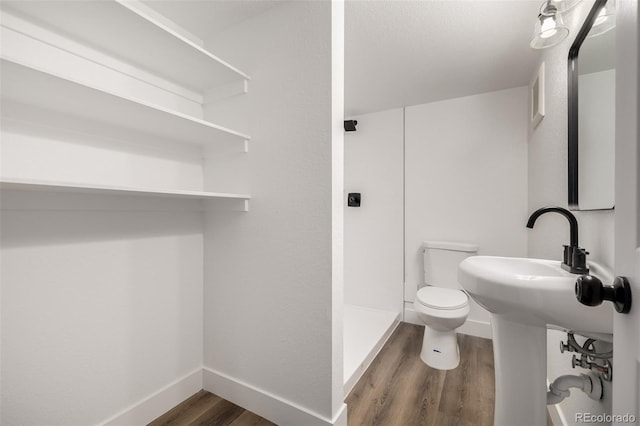 bathroom with wood-type flooring, a shower, and toilet