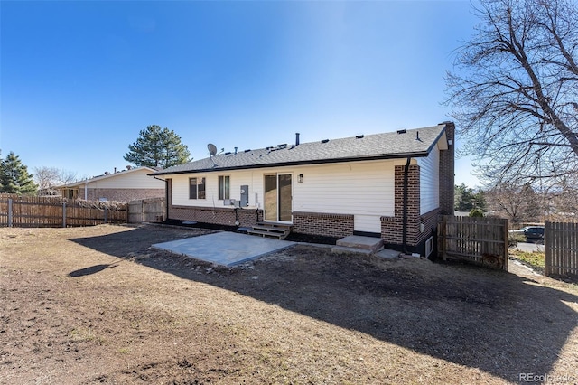 back of property with entry steps, brick siding, a patio area, and fence