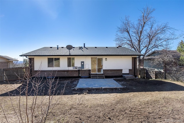 rear view of property with entry steps, a patio area, brick siding, and fence