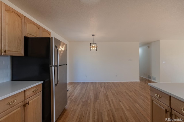 kitchen with light wood-type flooring, visible vents, light countertops, and freestanding refrigerator