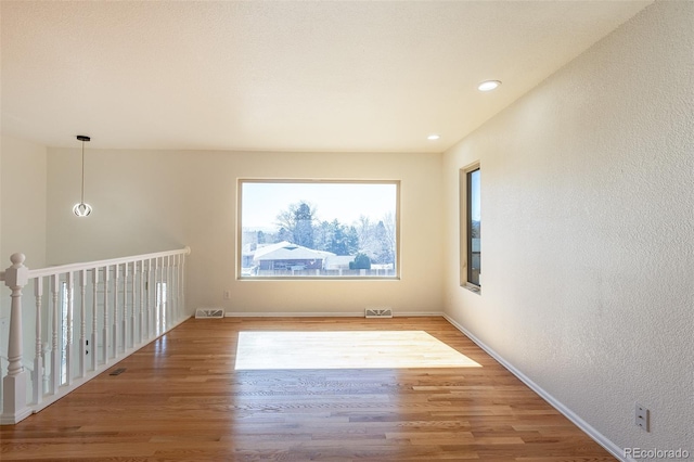 unfurnished room with a textured wall, wood finished floors, visible vents, and recessed lighting