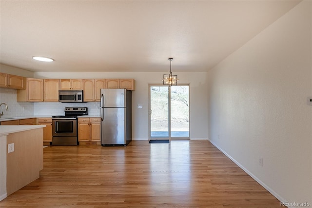 kitchen with stainless steel appliances, light brown cabinetry, light countertops, and decorative backsplash