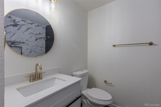 bathroom with a textured wall, vanity, and toilet