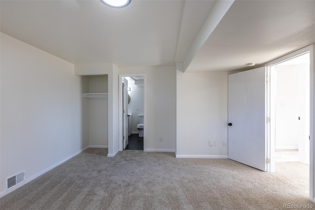 unfurnished bedroom featuring ensuite bathroom, carpet flooring, visible vents, and baseboards