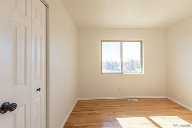 unfurnished room with light wood-style flooring, visible vents, and baseboards