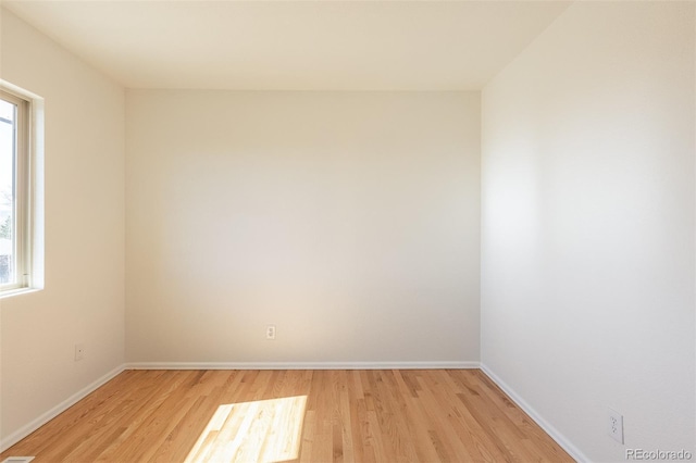 spare room with baseboards, a healthy amount of sunlight, and light wood finished floors