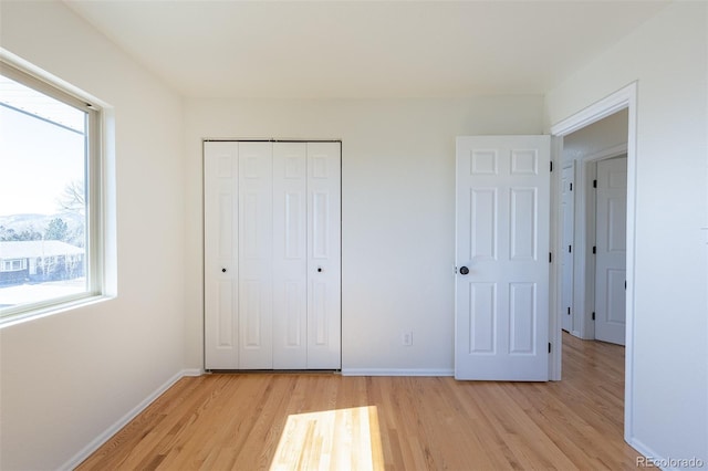 unfurnished bedroom featuring a closet, light wood-type flooring, and baseboards