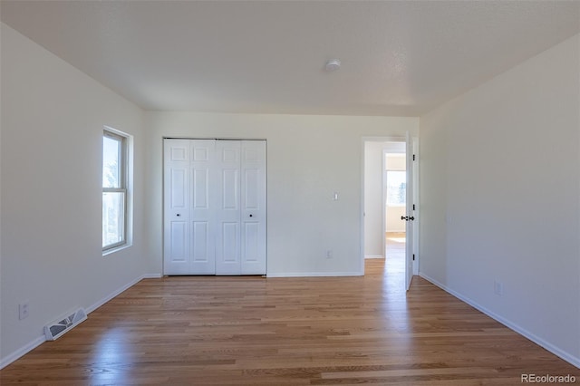 unfurnished bedroom with light wood-style floors, a closet, visible vents, and baseboards