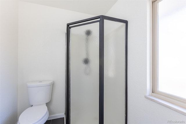 bathroom with a stall shower, toilet, and baseboards