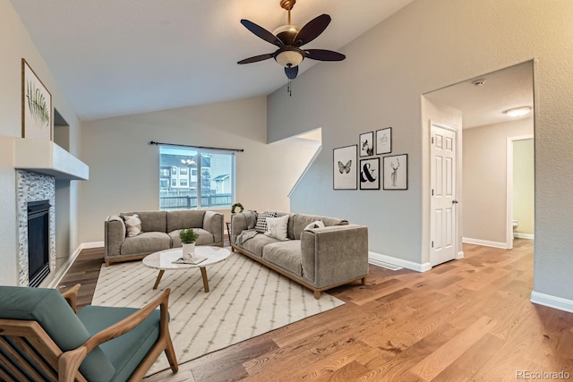 living room featuring a tile fireplace, light hardwood / wood-style floors, high vaulted ceiling, and ceiling fan