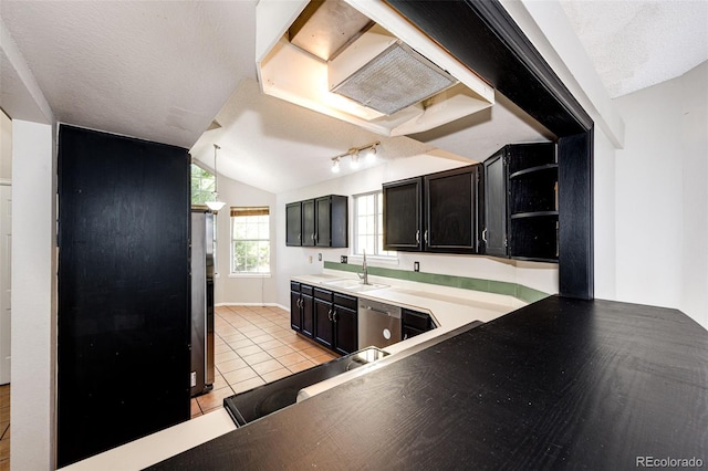 kitchen featuring lofted ceiling, sink, light tile patterned floors, stainless steel dishwasher, and a textured ceiling