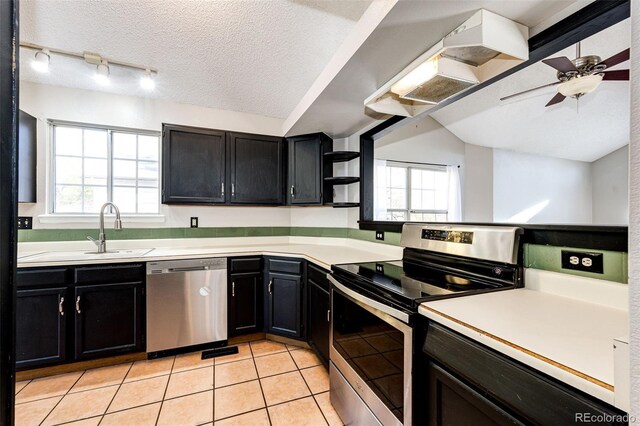 kitchen featuring ceiling fan, appliances with stainless steel finishes, light tile patterned floors, a textured ceiling, and vaulted ceiling