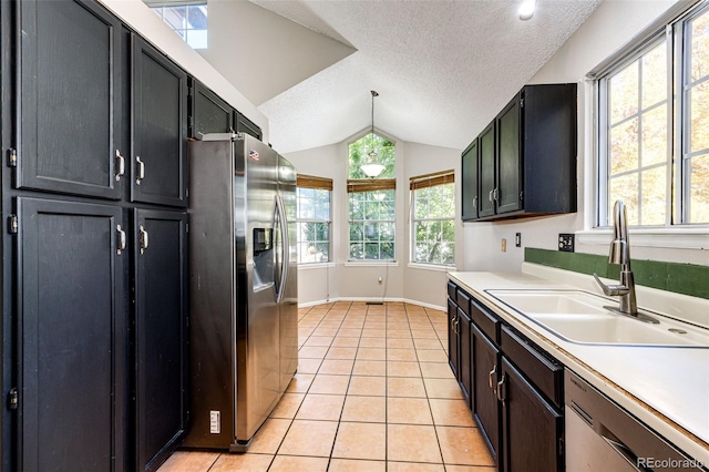 kitchen with a textured ceiling, appliances with stainless steel finishes, vaulted ceiling, and plenty of natural light