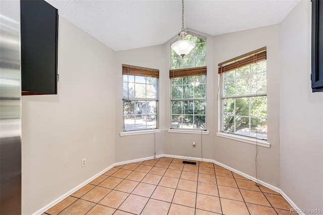 tiled spare room with lofted ceiling, a textured ceiling, and a healthy amount of sunlight