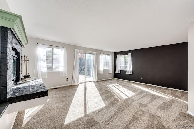 unfurnished living room with a wealth of natural light, a brick fireplace, and light colored carpet