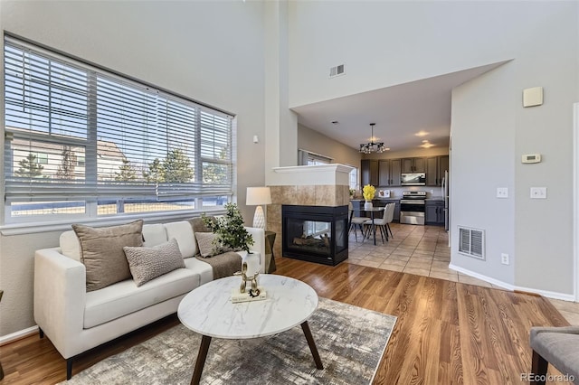 living area featuring visible vents, light wood-style flooring, and a tiled fireplace