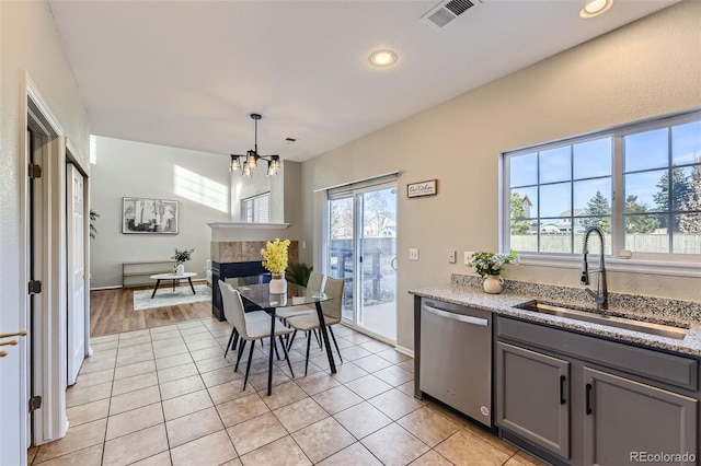 kitchen featuring visible vents, gray cabinetry, a sink, a fireplace, and dishwasher