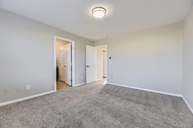 carpeted spare room featuring baseboards