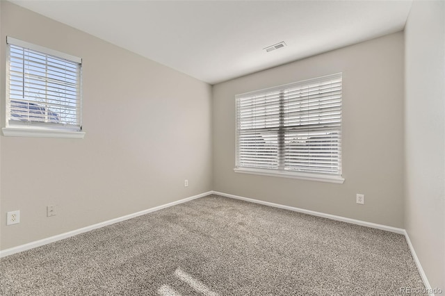 carpeted empty room featuring visible vents and baseboards