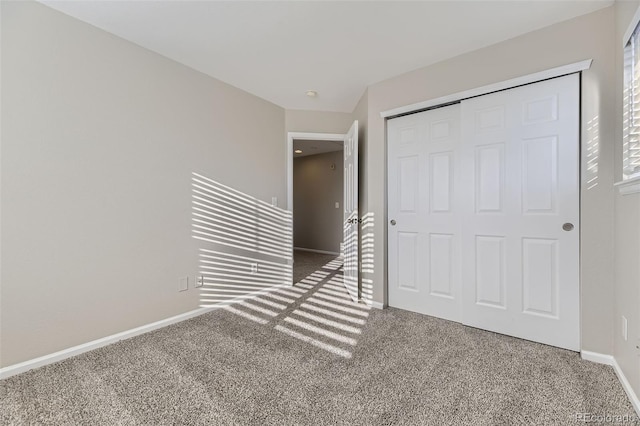 unfurnished bedroom featuring baseboards, carpet floors, and a closet