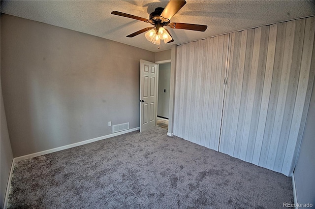 unfurnished bedroom featuring a ceiling fan, visible vents, a textured ceiling, and light colored carpet