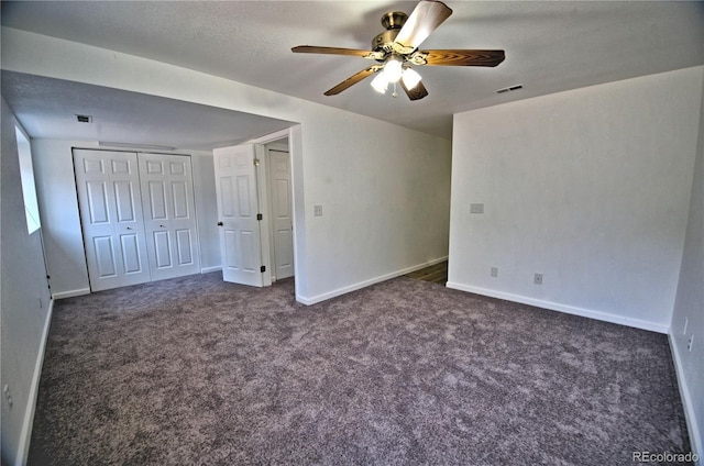 unfurnished bedroom with dark colored carpet, a ceiling fan, visible vents, and baseboards