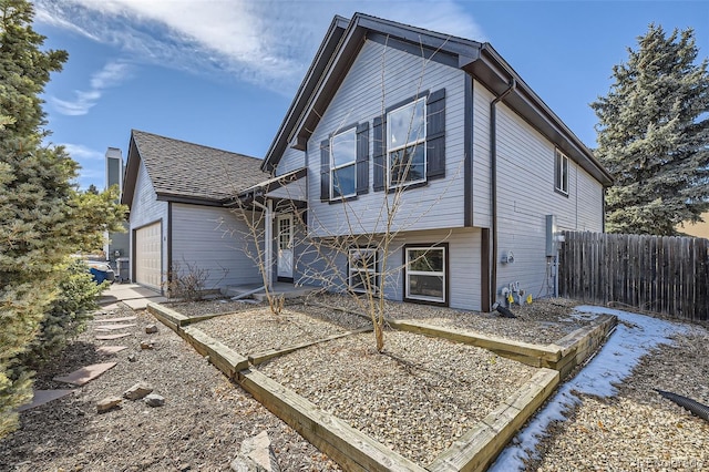 view of front of property with a garage, fence, and roof with shingles