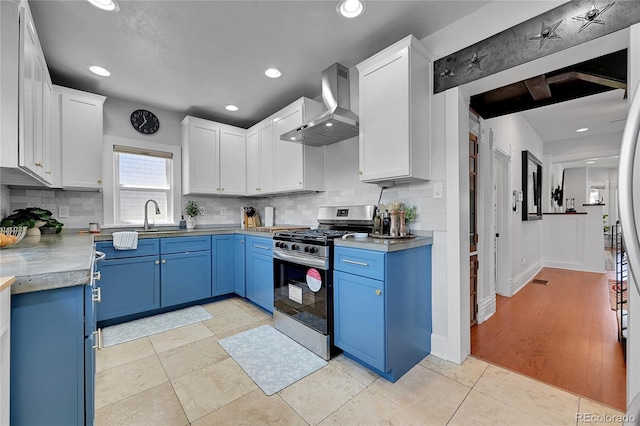 1208 S Pennsylvania St, Denver, CO 80210 - kitchen with stainless steel gas stove, wall chimney exhaust hood, blue cabinetry, white cabinets, and recessed lighting