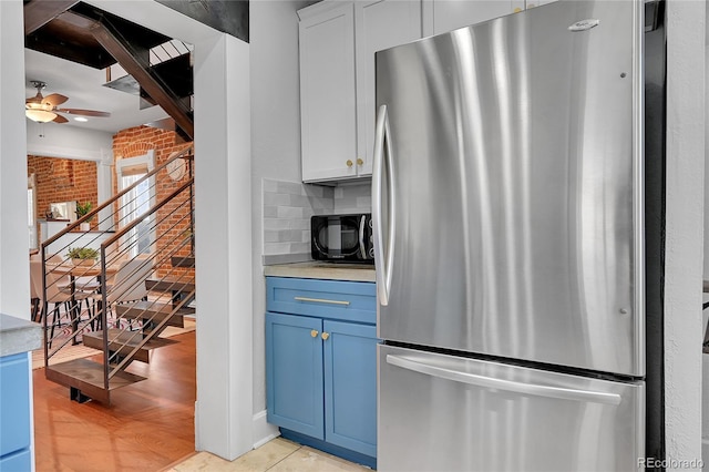 1208 S Pennsylvania St, Denver, CO 80210 - kitchen featuring freestanding refrigerator, blue cabinetry, a ceiling fan, black microwave, and tasteful backsplash