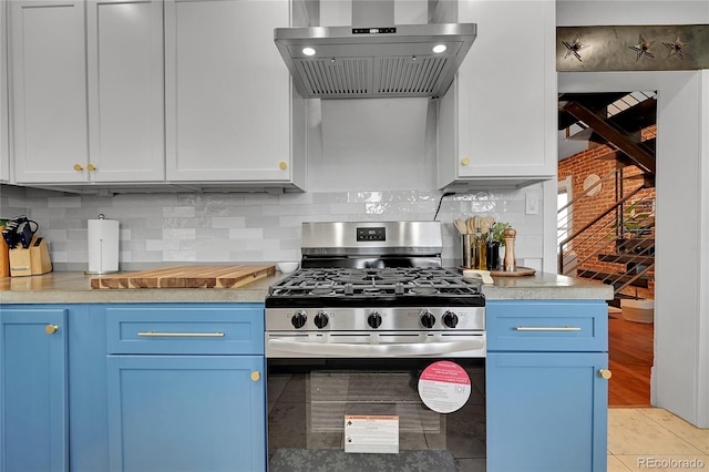 1208 S Pennsylvania St, Denver, CO 80210 - kitchen featuring stainless steel range with gas stovetop, wall chimney range hood, blue cabinetry, light countertops, and decorative backsplash