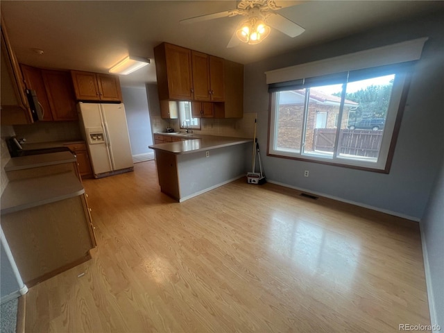 kitchen with stove, light wood-type flooring, ceiling fan, sink, and white fridge with ice dispenser