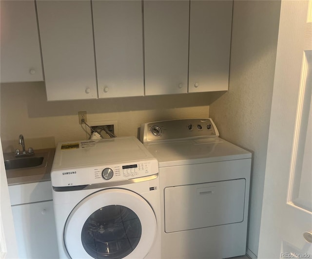 laundry area featuring cabinets, washing machine and dryer, and sink