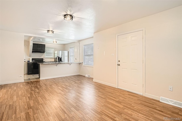 unfurnished living room featuring a textured ceiling and light hardwood / wood-style flooring