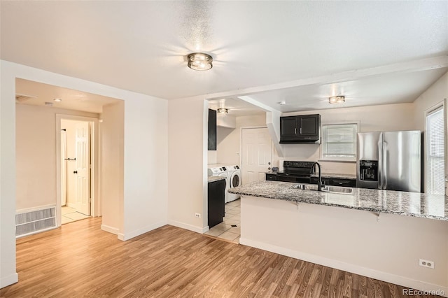 kitchen featuring stainless steel fridge with ice dispenser, light wood-type flooring, separate washer and dryer, and sink