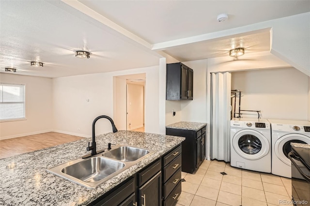 clothes washing area featuring washing machine and dryer, sink, and light tile patterned flooring