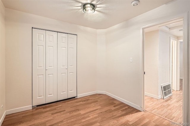 unfurnished bedroom with light wood-type flooring and a closet