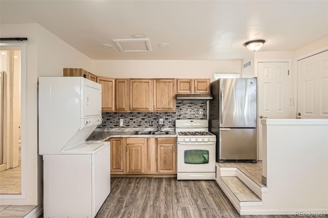 kitchen featuring stainless steel refrigerator, sink, dark wood-type flooring, stacked washer / drying machine, and white range with gas cooktop