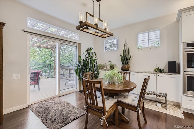 dining space with a healthy amount of sunlight, dark hardwood / wood-style floors, and a notable chandelier