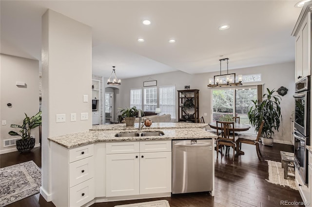 kitchen with appliances with stainless steel finishes, kitchen peninsula, sink, and white cabinets