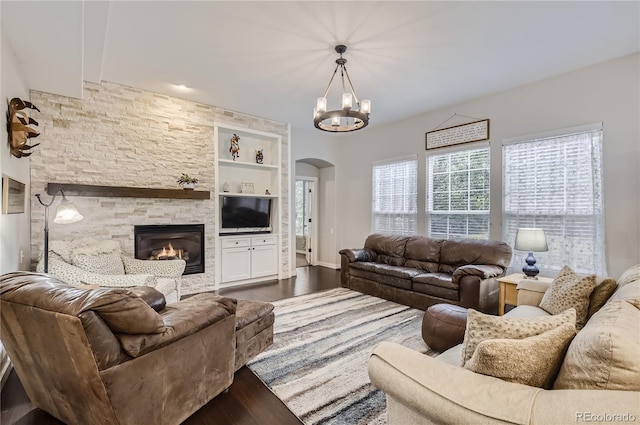 living room with hardwood / wood-style floors, built in shelves, a fireplace, and a notable chandelier