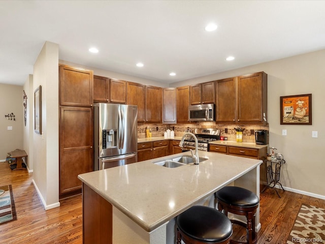 569 Jackson St, Lafayette, CO 80026 - kitchen with stainless steel appliances, light wood-type flooring, tasteful backsplash, brown cabinetry, and recessed lighting