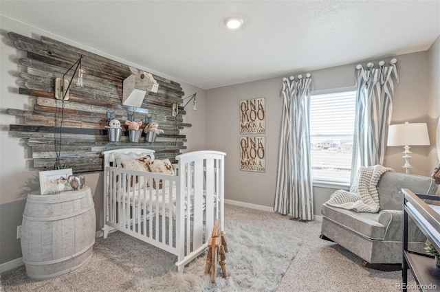 bedroom with multiple windows, a nursery area, and carpet flooring