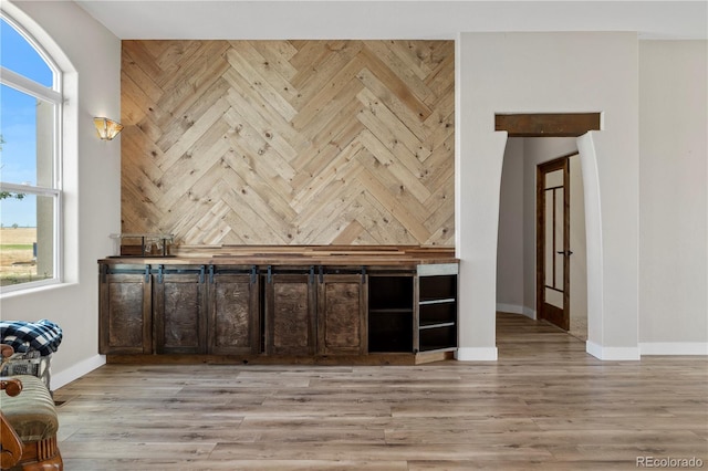 bar with dark brown cabinets and light wood-type flooring