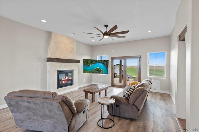 living room featuring ceiling fan, a fireplace, and light hardwood / wood-style floors